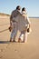 Senior couple walking barefoot on wet sand at seashore