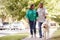 Senior Couple Walking Dog Along Suburban Street