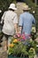 Senior Couple walking in plant nursery pulling cart of flowers back view