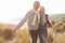 Senior Couple Walking Through Sand Dunes On Winter Beach