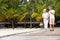 Senior Couple Walking On Wooden Jetty