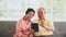 Senior couple waving and laughing with family in Video calling technology on table.