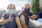 Senior couple wearing face mask virus protection and showing bandage injection covid-19 vaccinated with thumb up