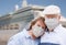 Senior Couple Wearing Face Masks Standing In Front of Passenger Cruise Ship