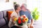 Senior couple. The wife thanks with a kiss for the flowers received. Two caucasian people in relaxing moment sitted on the sofa in