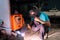 Senior Craftsman, wearing a welding helmet, sitting very skilled and careful welding, on his chair in a small factory