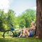 Senior cyclist sitting by a tree in park