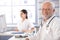 Senior doctor sitting at desk smiling