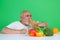 Senior drink orange juice near vegetables in studio. Elderly man hold glass of orange juice and vegetables. Orange juice