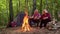 Senior elderly grandmother grandfather cooking frying sausages over campfire in wood at camping