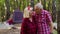 Senior elderly grandmother grandfather tourists resting at camping in wood over bonfire at camping