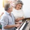 Senior elderly man plays piano in nursing home listened to by elderly woman,Retreatment elderly asian grandmother and grandfather