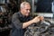 Senior engineer checking old used car engine in machinery parts shop warehouse. old technician man Repair vehicle automobile