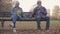 Senior European couple sitting on the bench separately. Mature Caucasian man taking hand of his lovely wife, family