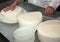 Senior expert cheesemaker checks he wheel of cheese just made in