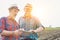 Senior farmer discussing over digital tablet to mature farmer against tractor