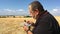 Senior farmer eating steamed vegetables sitting outdoor against harvested wheat field and blue sky