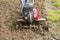 Senior farmer gardener working in the garden with rototiller , tiller tractor, cutivator, miiling machine