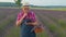 Senior farmer grandfather in field growing lavender, holding digital tablet and examining harvest