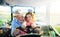 Senior farmer with small granddaughter sitting in tractor, driving.