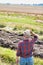 Senior farmer standing while holding his hat in field