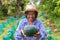 Senior farmer woman hold watermelon in farm. Focus on watermelon