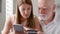 Senior father and his young daughter using smartphone at home. Shopping with credit card on cellphone