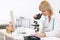 Senior female doctor looking in microscope at lab