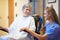 Senior Female Patient Being Pushed In Wheelchair By Nurse