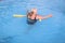 Senior female woman holds on to a flotation device on a swimming pool to learn how to swim