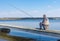 Senior fisherman sitting on wicker stool on a pier with rod and ready to catch fish