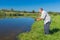 Senior fisherman standing on a riverside