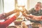 Senior friends cheering with wine glasses at home lunch - Happy mature people having fun together - Focus on left bottom glass -