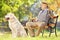 Senior gentleman seated on bench with his dog relaxing in park