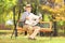 Senior gentleman seated on a bench reading a newspaper