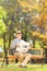 Senior gentleman seated on a bench reading a newspaper in a park