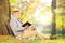 Senior gentleman sitting on a grass and reading a novel in park