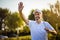 Senior golfer on golf court waving to someone.  Smiling golfer