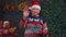Senior grandfather in Christmas sweater smiling friendly at camera and waving hands gesturing hello