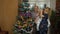 Senior grandfather, grandmother and granddaughter child lights garlands on artificial Christmas tree