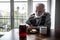 Senior grandfather with grey hair and beard sitting alone in the kitchen eating breakfast