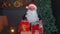 Senior grandfather parodies Santa Claus presenting Christmas gift box, holidays celebration at home