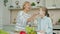 Senior grandmother making salad and feeding cute happy child with vegetable chops
