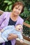 Senior grandmother sitting on becnh with grandchild laying on arms, elder woman with infant portrait