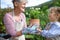 Senior grandmother with small granddaughter gardening on balcony in summer.