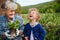 Senior grandmother with small granddaughter gardening on balcony in summer, laughing.