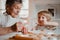 A senior grandmother with small toddler boy making cakes at home.