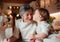 Senior grandmother with small toddler children making cakes at home.