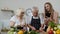 Senior grandparents couple cutting vegetables for salad, listening recipe from girl with tablet