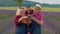 Senior grandparents granddaughter farmers growing lavender plant in garden field, family business